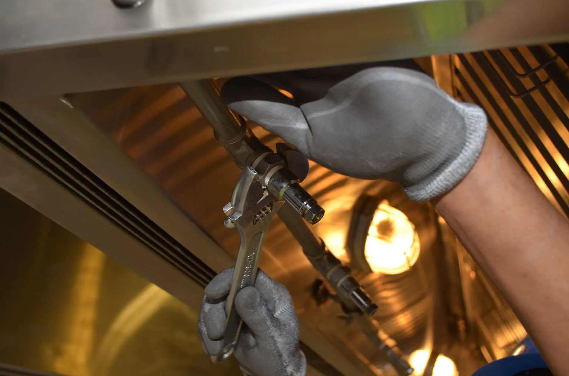 Plumber tightening a fitting under a residential kitchen sink